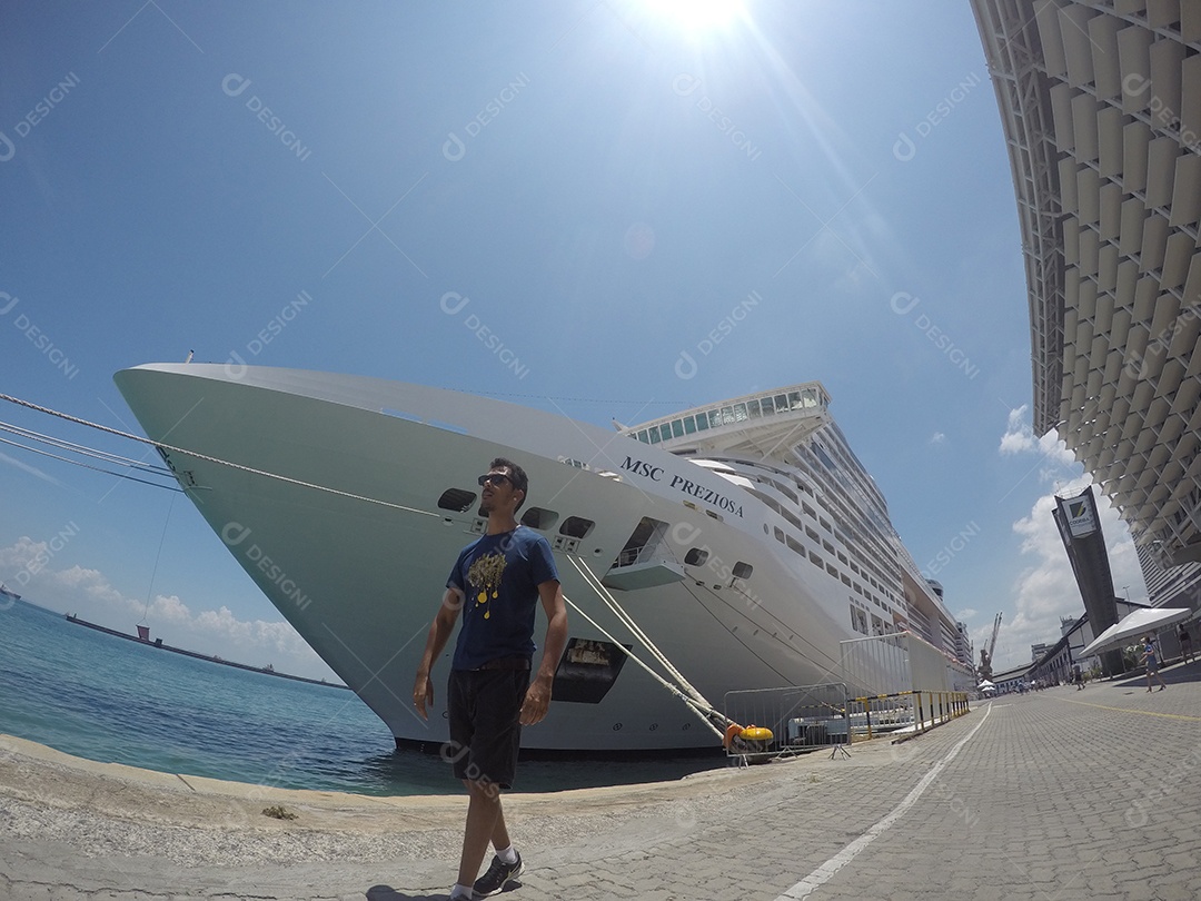 Retrato de um jovem turista negro em frente a um navio de cruzeiro em um céu nublado