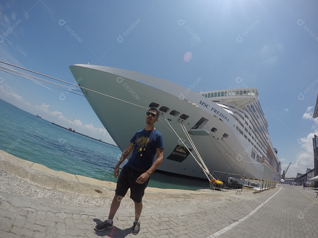 Retrato de um jovem turista negro em frente a um navio de cruzeiro em um céu nublado