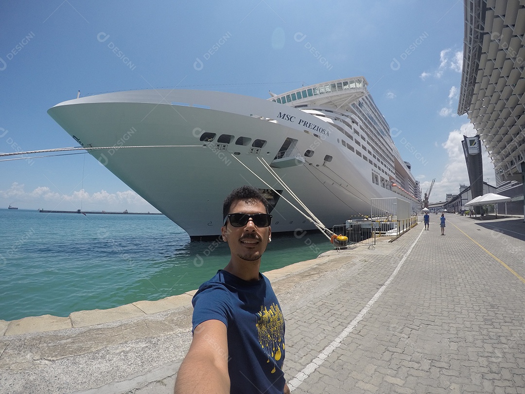 Retrato de um jovem turista negro em frente a um navio de cruzeiro em um céu nublado