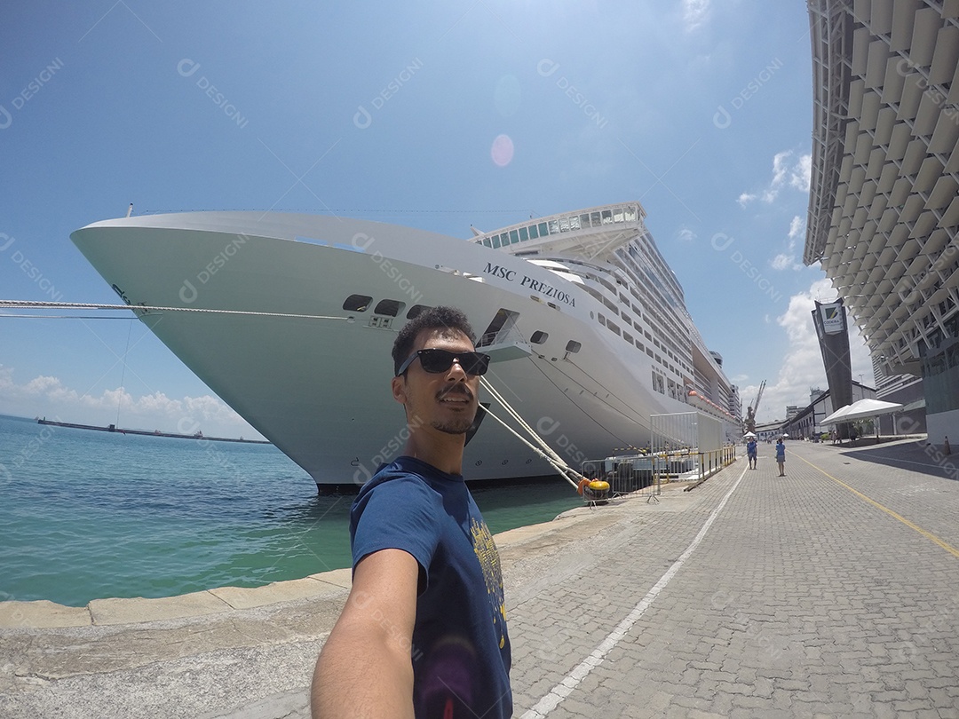 Retrato de um jovem turista negro em frente a um navio de cruzeiro em um céu nublado