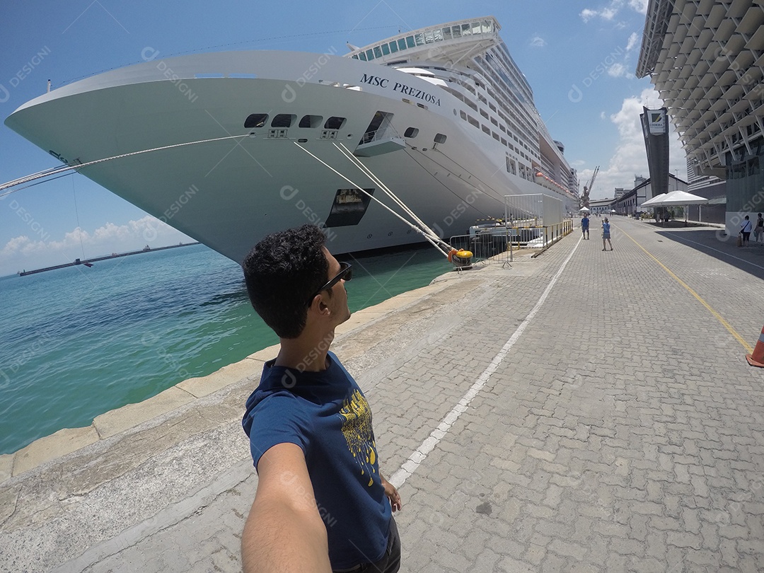 Retrato de um jovem turista negro em frente a um navio de cruzeiro em um céu nublado