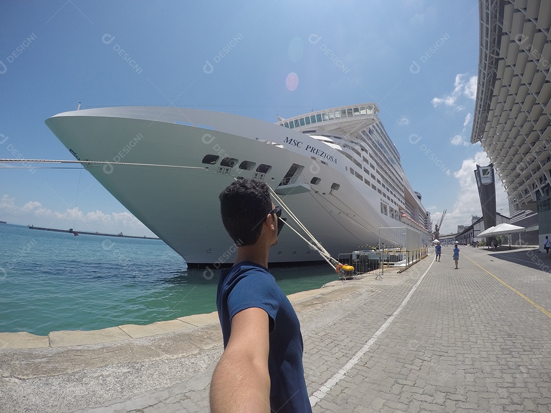 Retrato de um jovem turista negro em frente a um navio de cruzeiro em um céu nublado