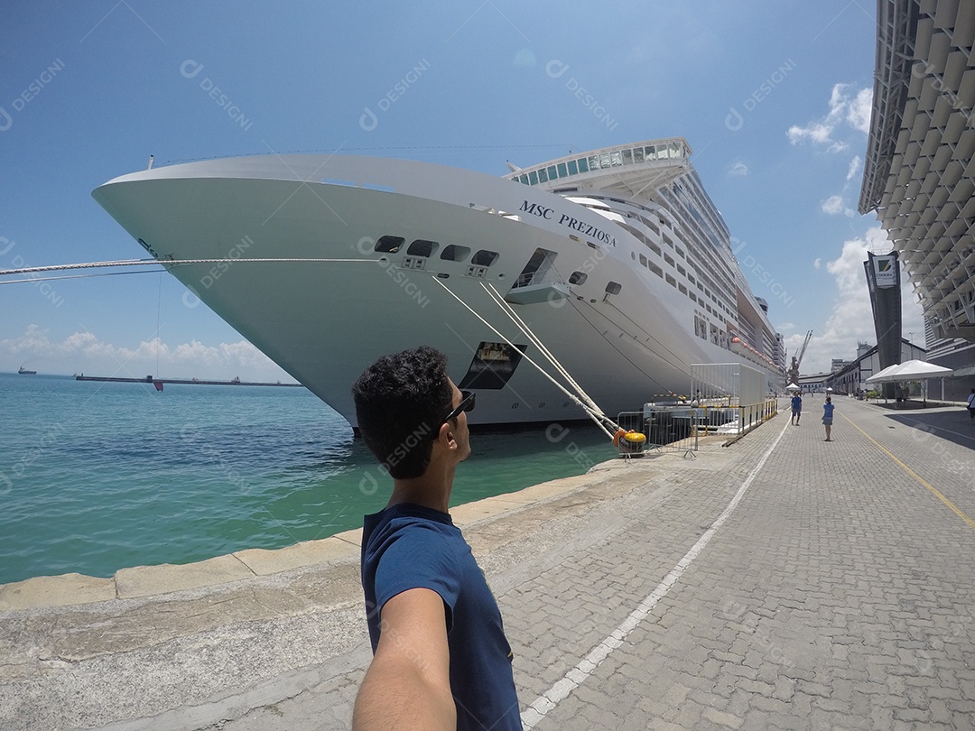 Retrato de um jovem turista negro em frente a um navio de cruzeiro em um céu nublado