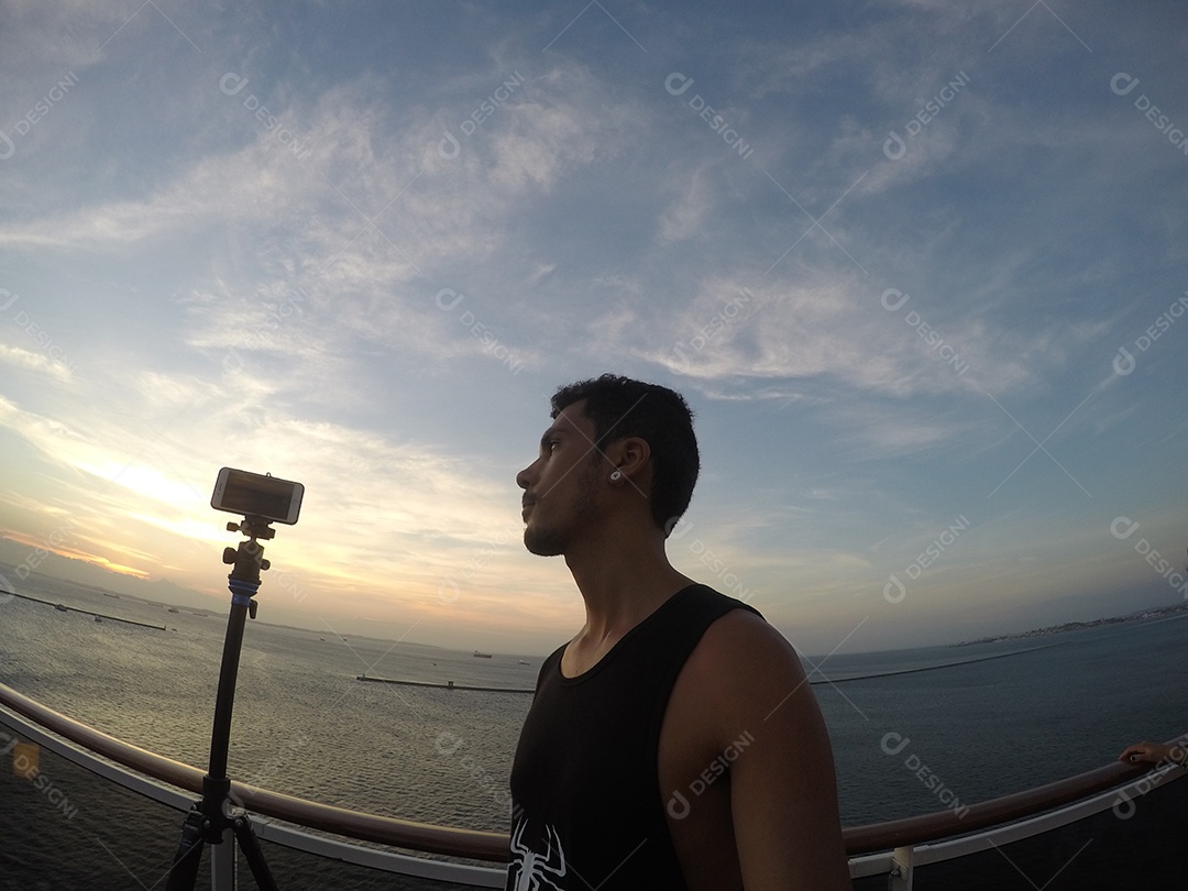 Retrato de um jovem turista negro no convés de um navio de cruzeiro em frente ao pôr do sol