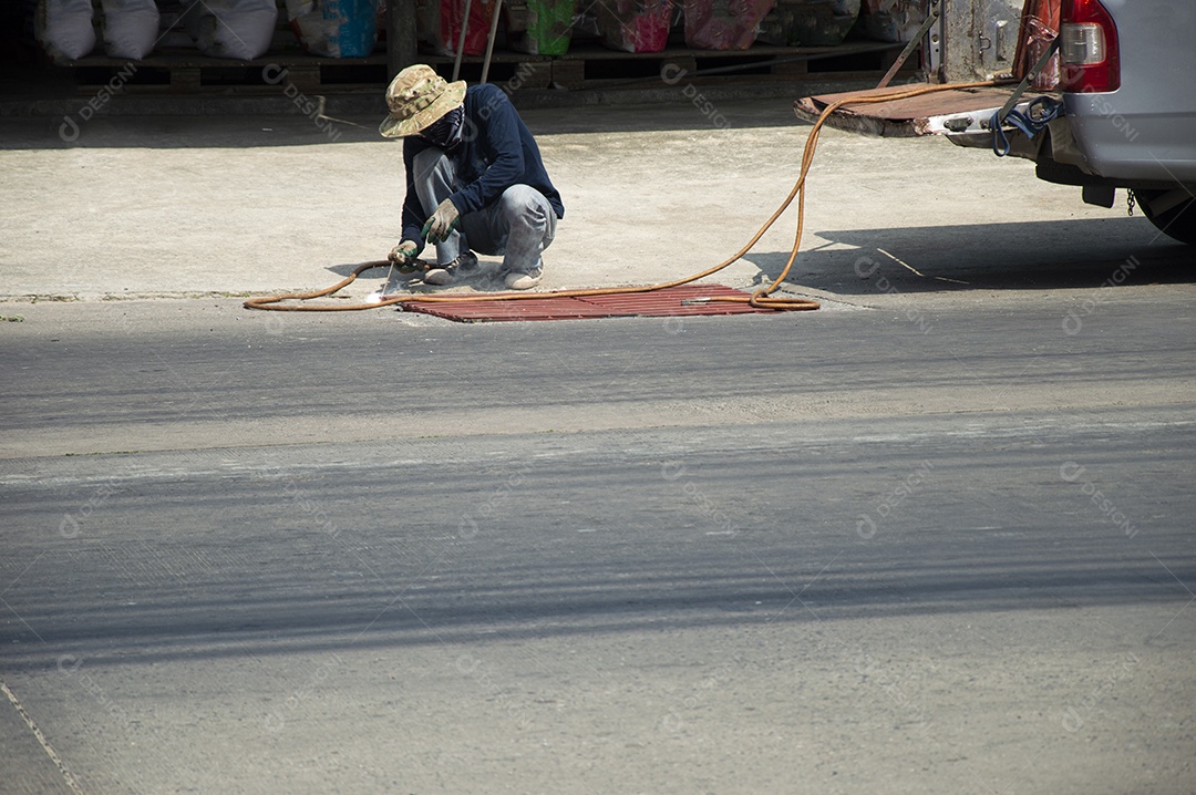 Técnicos estão reparando e soldando uma tampa de bueiro em uma estrada