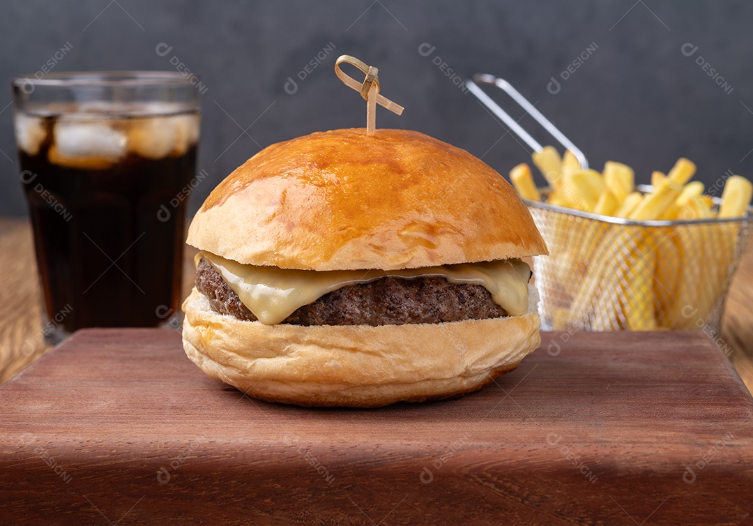 Cheeseburger sobre tábua de madeira com batata frita e refrigerante.