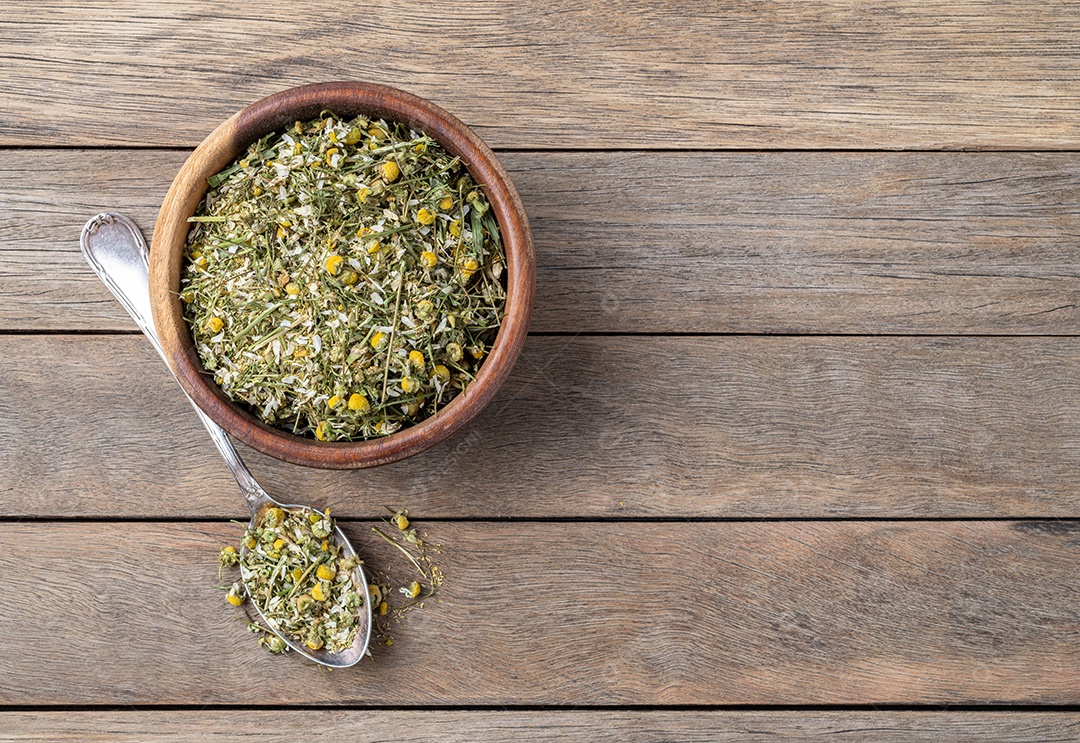 Camomila dentro de tigela e colher encima da mesa