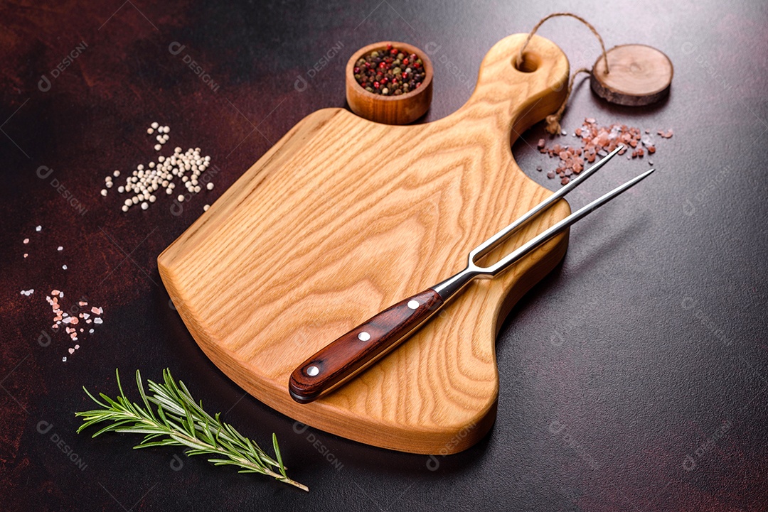 Tábua de corte com sal, especiarias e ervas sobre um fundo escuro de concreto. Cozinhar alimentos saudáveis