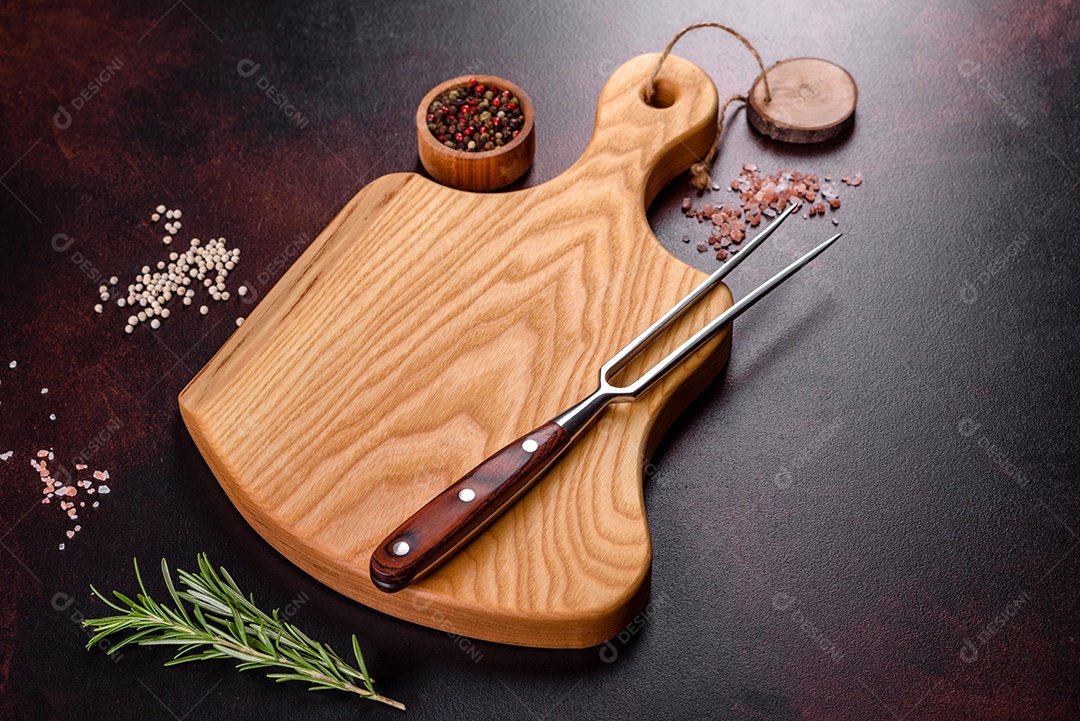 Tábua de corte com sal, especiarias e ervas sobre um fundo escuro de concreto. Cozinhar alimentos saudáveis