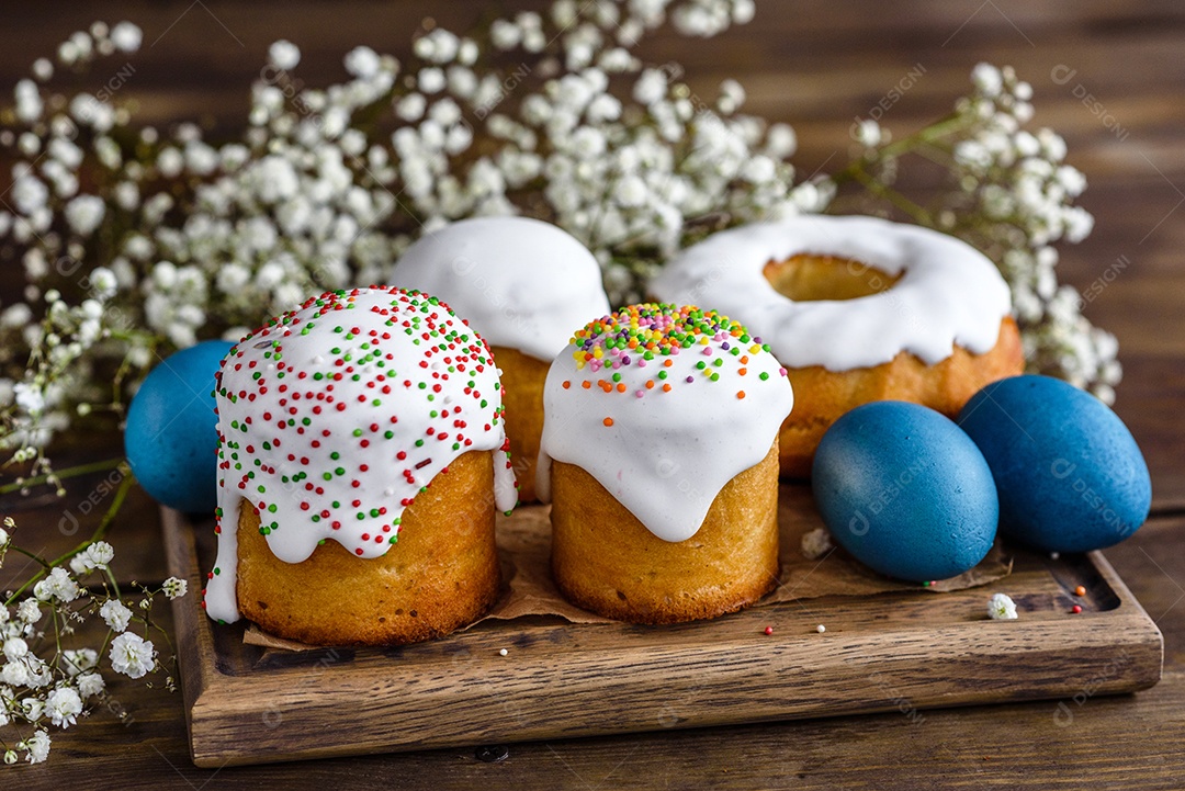 Bolos festivos com esmalte branco, nozes e passas com ovos de Páscoa na mesa festiva. Preparativos para a Páscoa