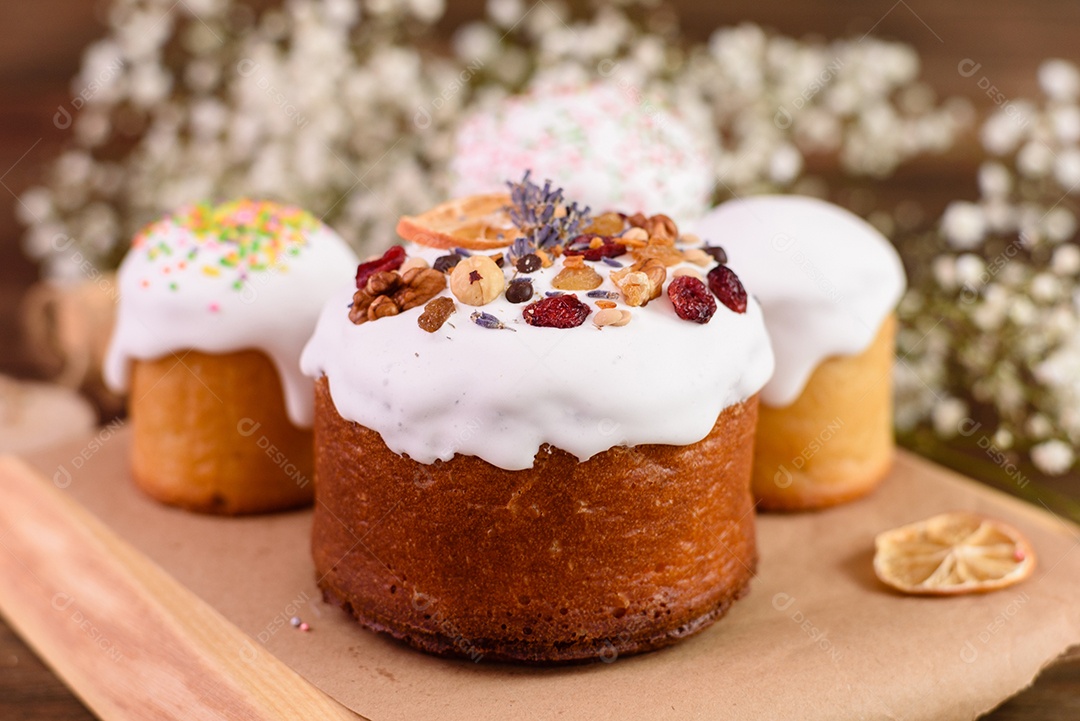 Bolos festivos com esmalte branco, nozes e passas com ovos de Páscoa na mesa festiva. Preparativos para a Páscoa