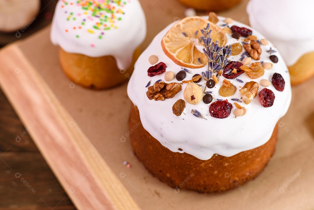 Bolos festivos com esmalte branco, nozes e passas com ovos de Páscoa na mesa festiva. Preparativos para a Páscoa