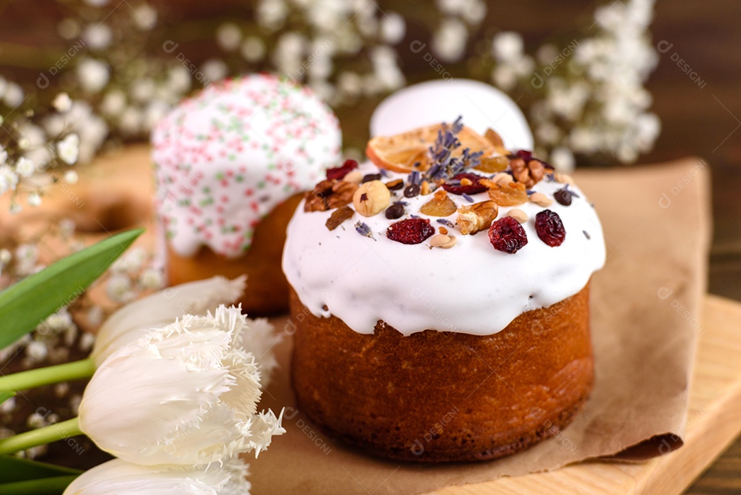 Bolos festivos com esmalte branco, nozes e passas com ovos de Páscoa na mesa festiva. Preparativos para a Páscoa