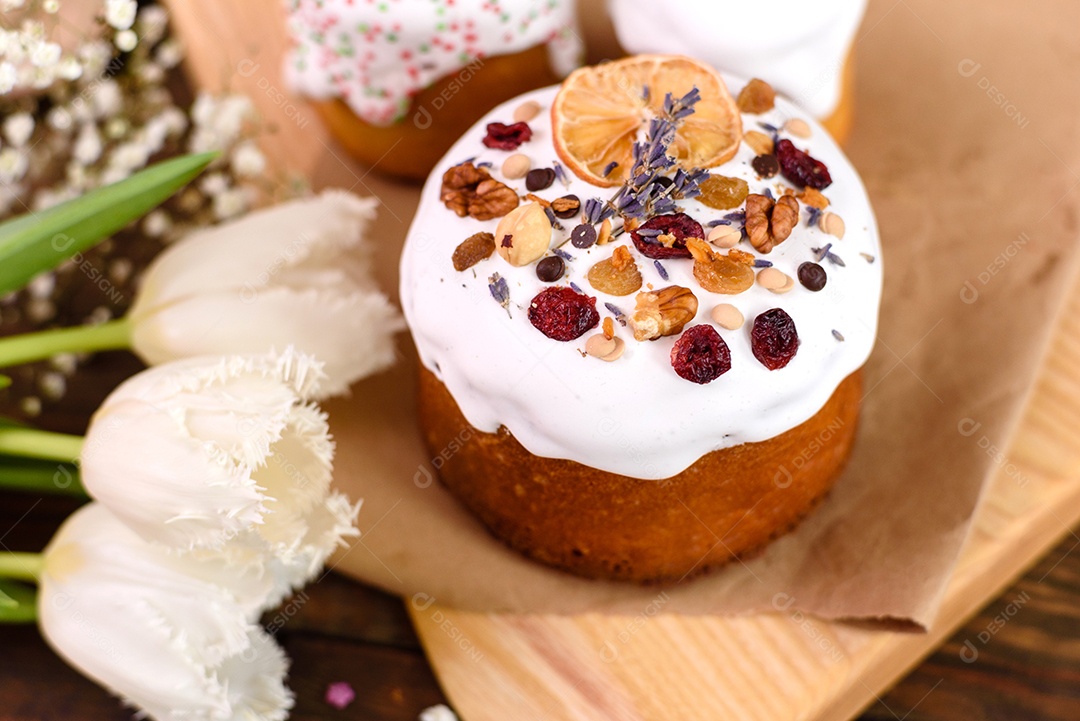 Bolos festivos com esmalte branco, nozes e passas com ovos de Páscoa na mesa festiva. Preparativos para a Páscoa