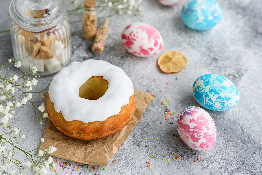 Bolos festivos com esmalte branco, nozes e passas com ovos de Páscoa na mesa festiva. Preparativos para a Páscoa