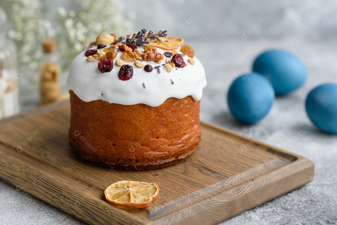 Bolos festivos com esmalte branco, nozes e passas com ovos de Páscoa na mesa festiva. Preparativos para a Páscoa