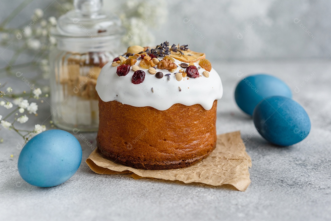 Bolos festivos com esmalte branco, nozes e passas com ovos de Páscoa na mesa festiva. Preparativos para a Páscoa