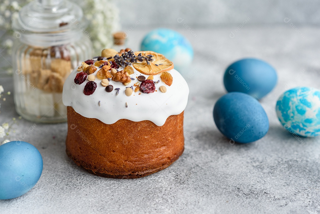 Bolos festivos com esmalte branco, nozes e passas com ovos de Páscoa na mesa festiva. Preparativos para a Páscoa