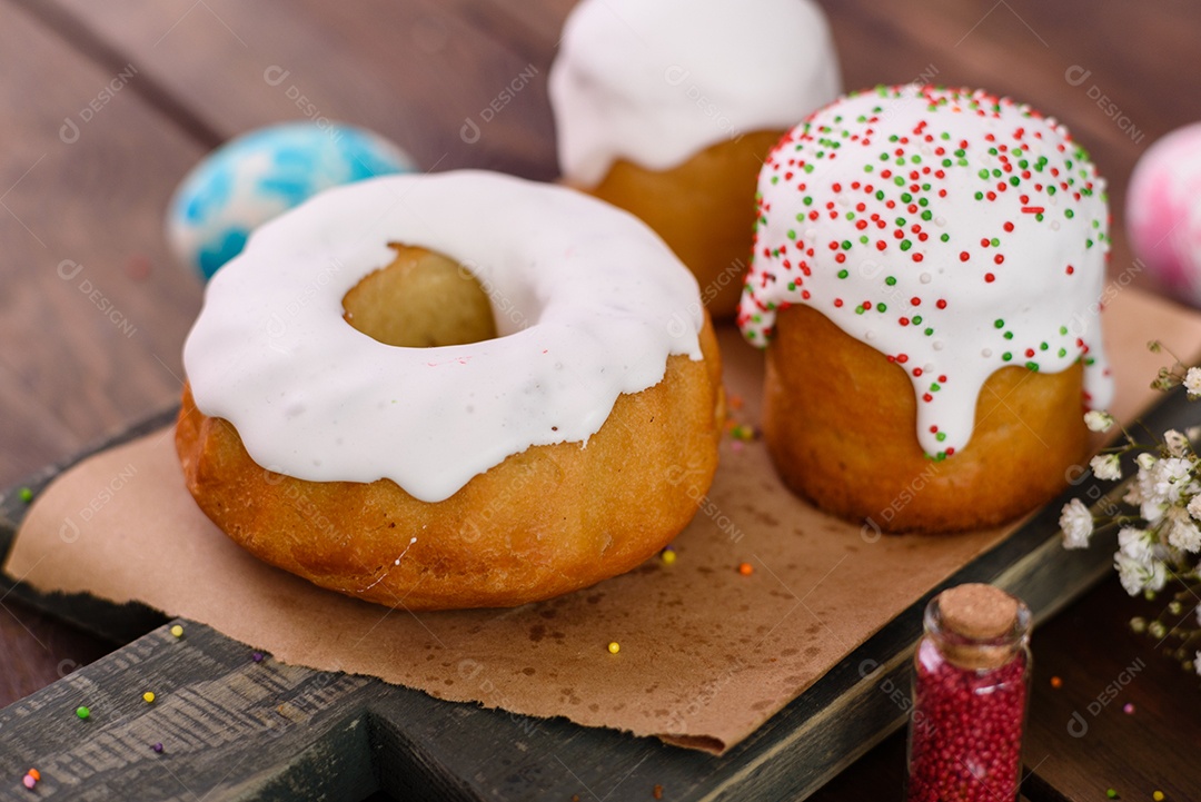 Bolos festivos com esmalte branco, nozes e passas com ovos de Páscoa na mesa festiva. Preparativos para a Páscoa
