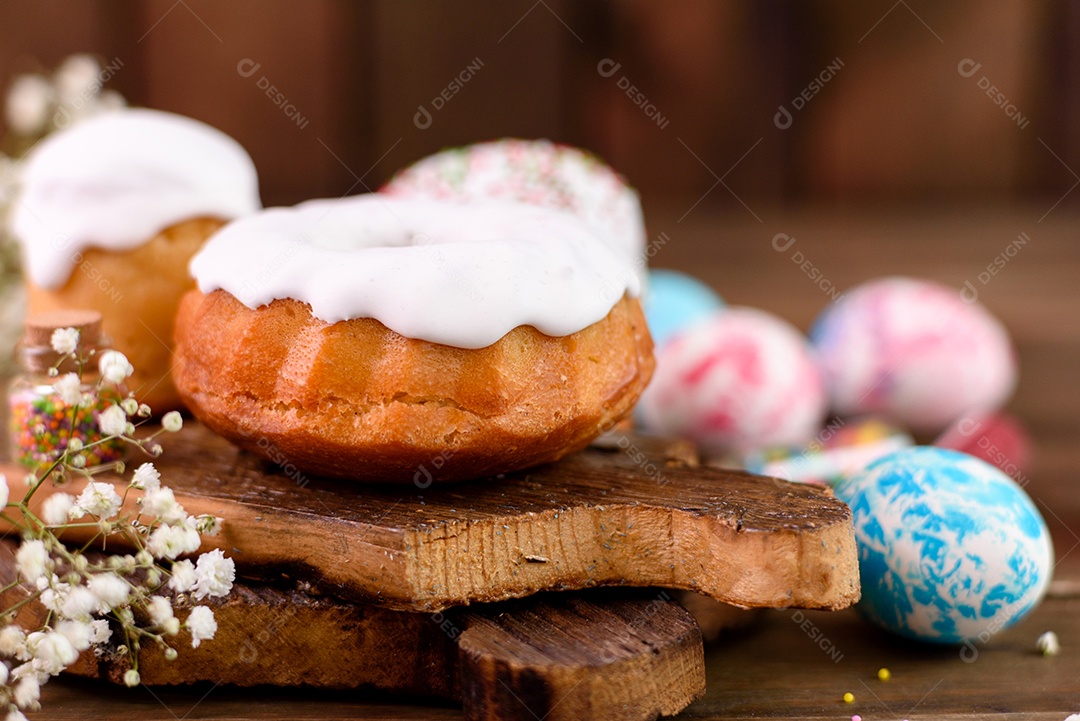 Bolos festivos com esmalte branco, nozes e passas com ovos de Páscoa na mesa festiva. Preparativos para a Páscoa