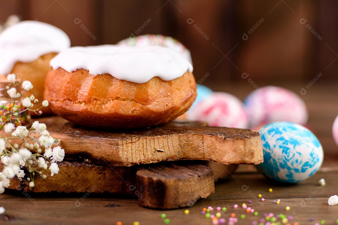 Bolos festivos com esmalte branco, nozes e passas com ovos de Páscoa na mesa festiva. Preparativos para a Páscoa