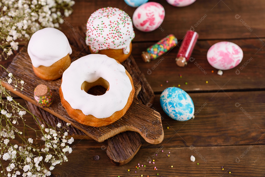 Bolos festivos com esmalte branco, nozes e passas com ovos de Páscoa na mesa festiva. Preparativos para a Páscoa