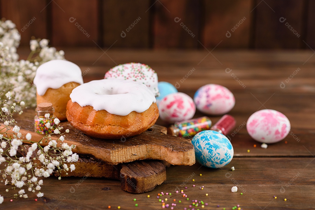 Bolos festivos com esmalte branco, nozes e passas com ovos de Páscoa na mesa festiva. Preparativos para a Páscoa