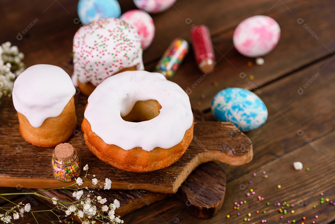 Bolos festivos com esmalte branco, nozes e passas com ovos de Páscoa na mesa festiva. Preparativos para a Páscoa