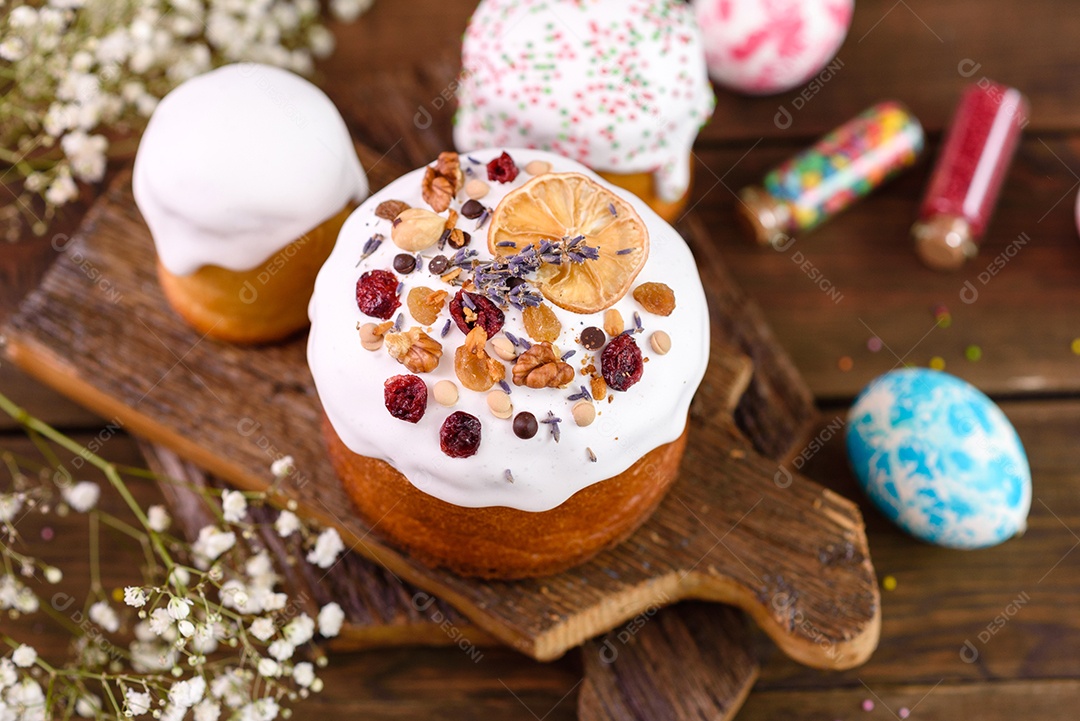 Bolos festivos com esmalte branco, nozes e passas com ovos de Páscoa na mesa festiva. Preparativos para a Páscoa