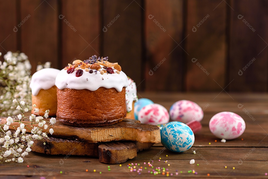 Bolos festivos com esmalte branco, nozes e passas com ovos de Páscoa na mesa festiva. Preparativos para a Páscoa