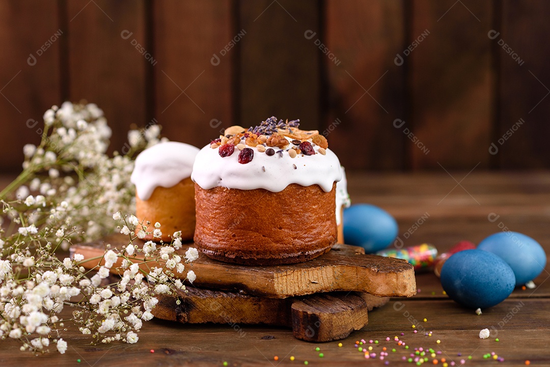 Bolos festivos com esmalte branco, nozes e passas com ovos de Páscoa na mesa festiva. Preparativos para a Páscoa