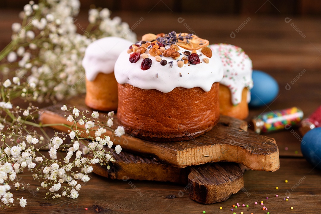 Bolos festivos com esmalte branco, nozes e passas com ovos de Páscoa na mesa festiva. Preparativos para a Páscoa
