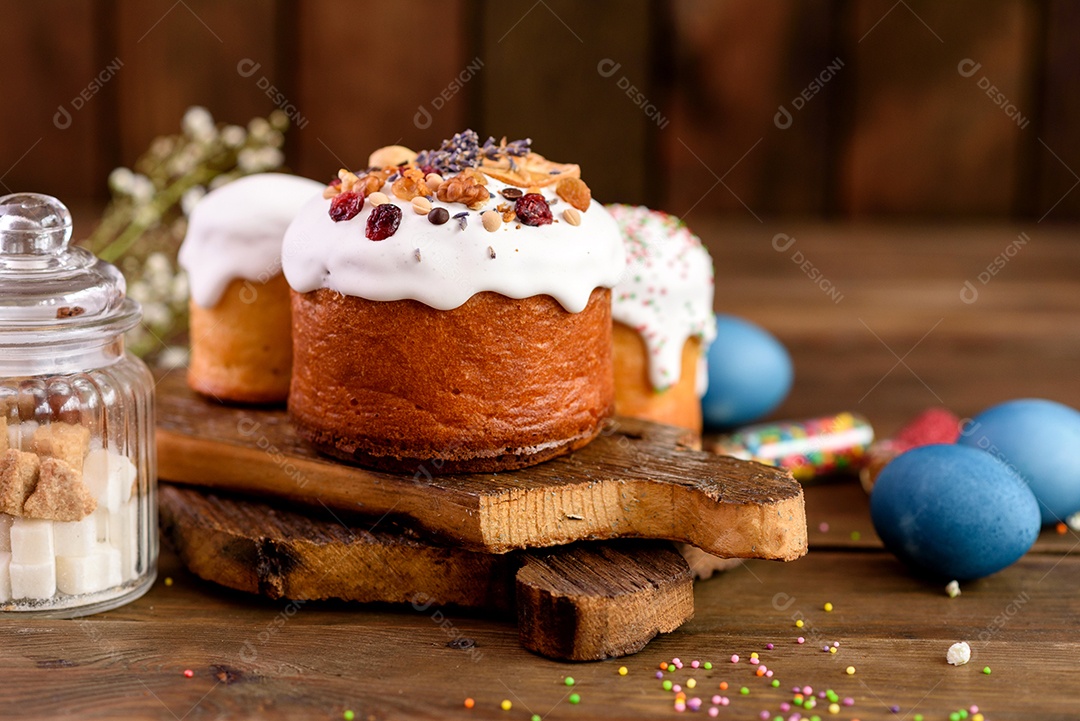 Bolos festivos com esmalte branco, nozes e passas com ovos de Páscoa na mesa festiva. Preparativos para a Páscoa