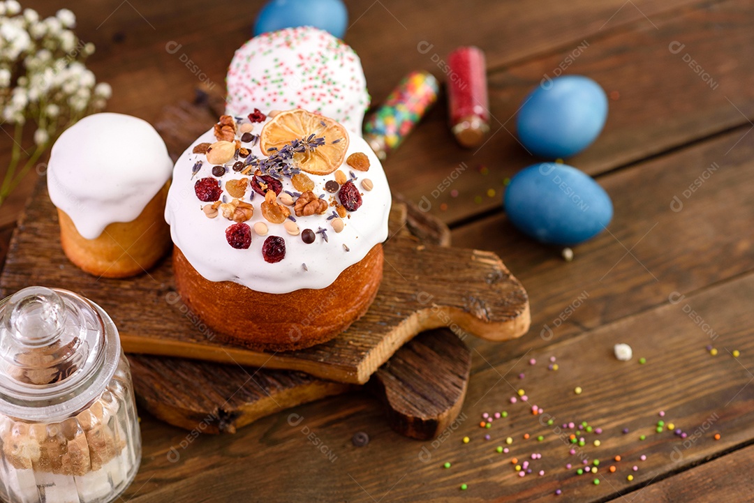 Bolos festivos com esmalte branco, nozes e passas com ovos de Páscoa na mesa festiva. Preparativos para a Páscoa