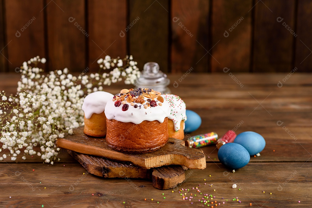 Bolos festivos com esmalte branco, nozes e passas com ovos de Páscoa na mesa festiva. Preparativos para a Páscoa