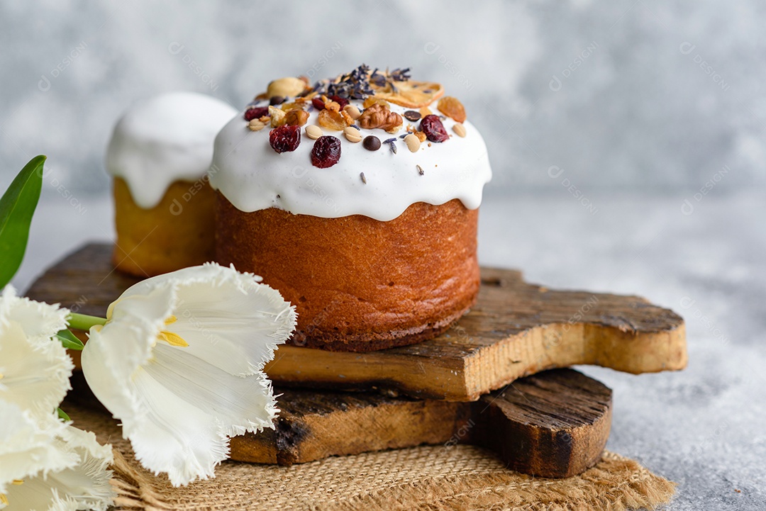 Bolos festivos com esmalte branco, nozes e passas com ovos de Páscoa na mesa festiva. Preparativos para a Páscoa