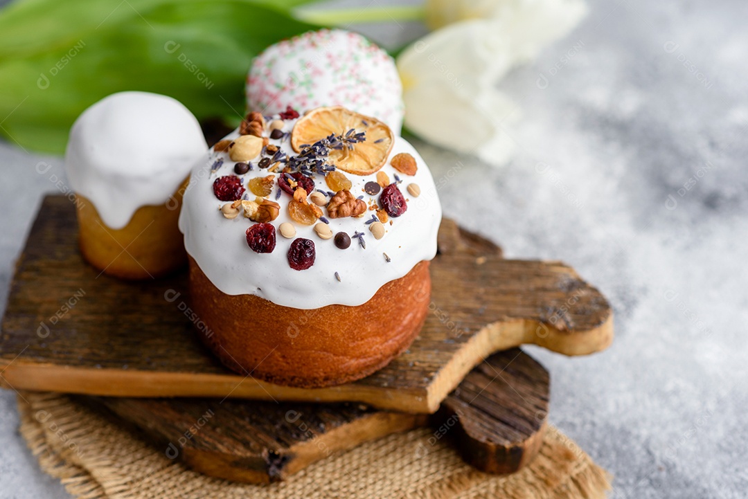 Bolos festivos com esmalte branco, nozes e passas com ovos de Páscoa na mesa festiva. Preparativos para a Páscoa