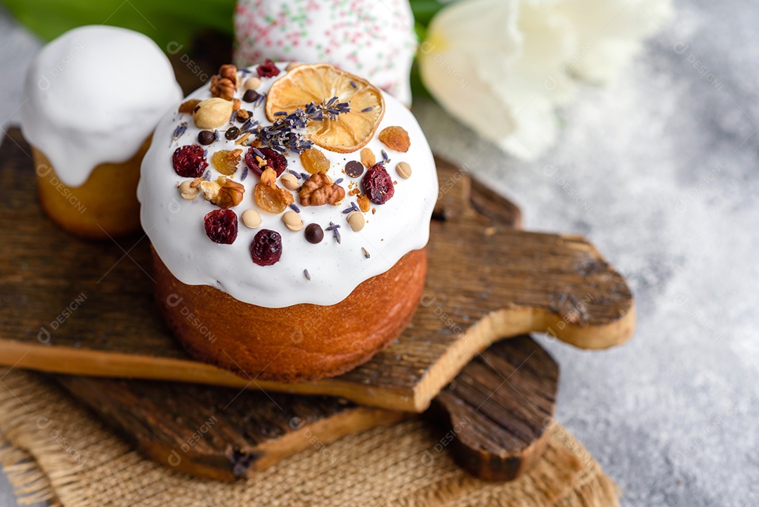 Bolos festivos com esmalte branco, nozes e passas com ovos de Páscoa na mesa festiva. Preparativos para a Páscoa