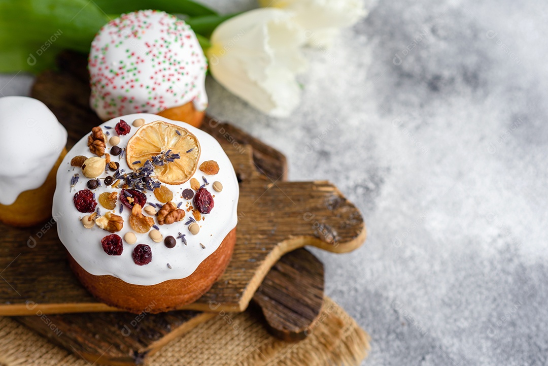 Bolos festivos com esmalte branco, nozes e passas com ovos de Páscoa na mesa festiva. Preparativos para a Páscoa