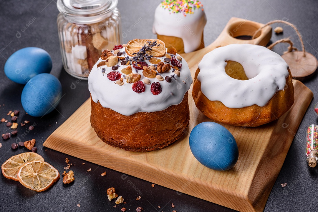 Bolos festivos com esmalte branco, nozes e passas com ovos de Páscoa na mesa festiva. Preparativos para a Páscoa