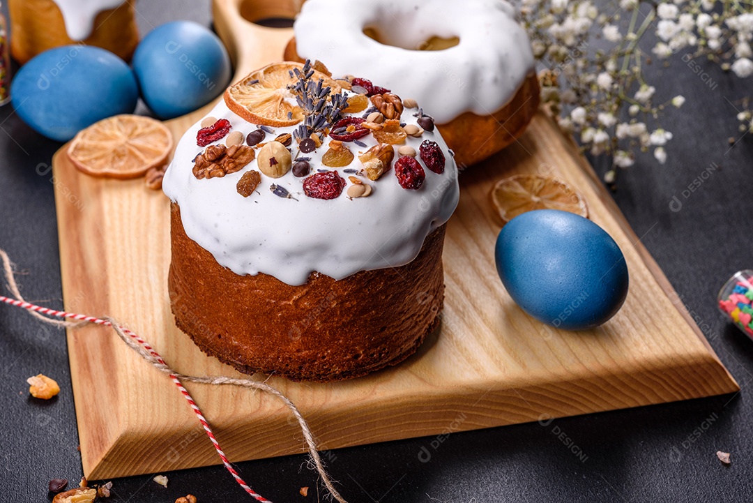 Bolos festivos com esmalte branco, nozes e passas com ovos de Páscoa na mesa festiva. Preparativos para a Páscoa