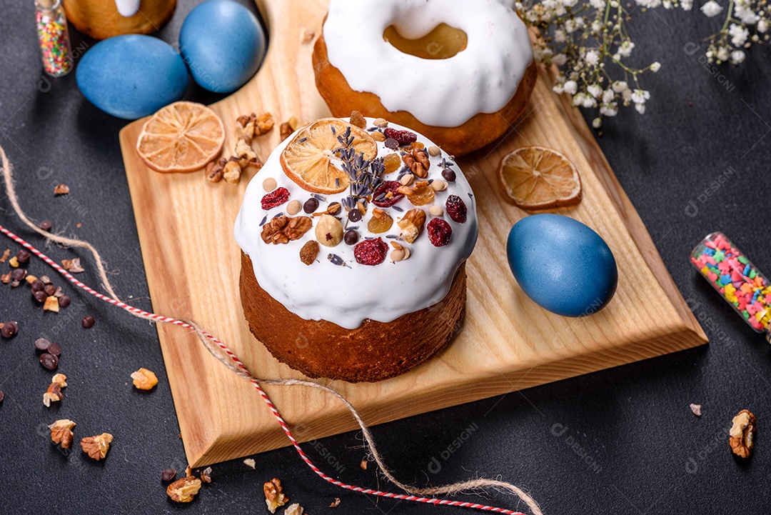Bolos festivos com esmalte branco, nozes e passas com ovos de Páscoa na mesa festiva. Preparativos para a Páscoa