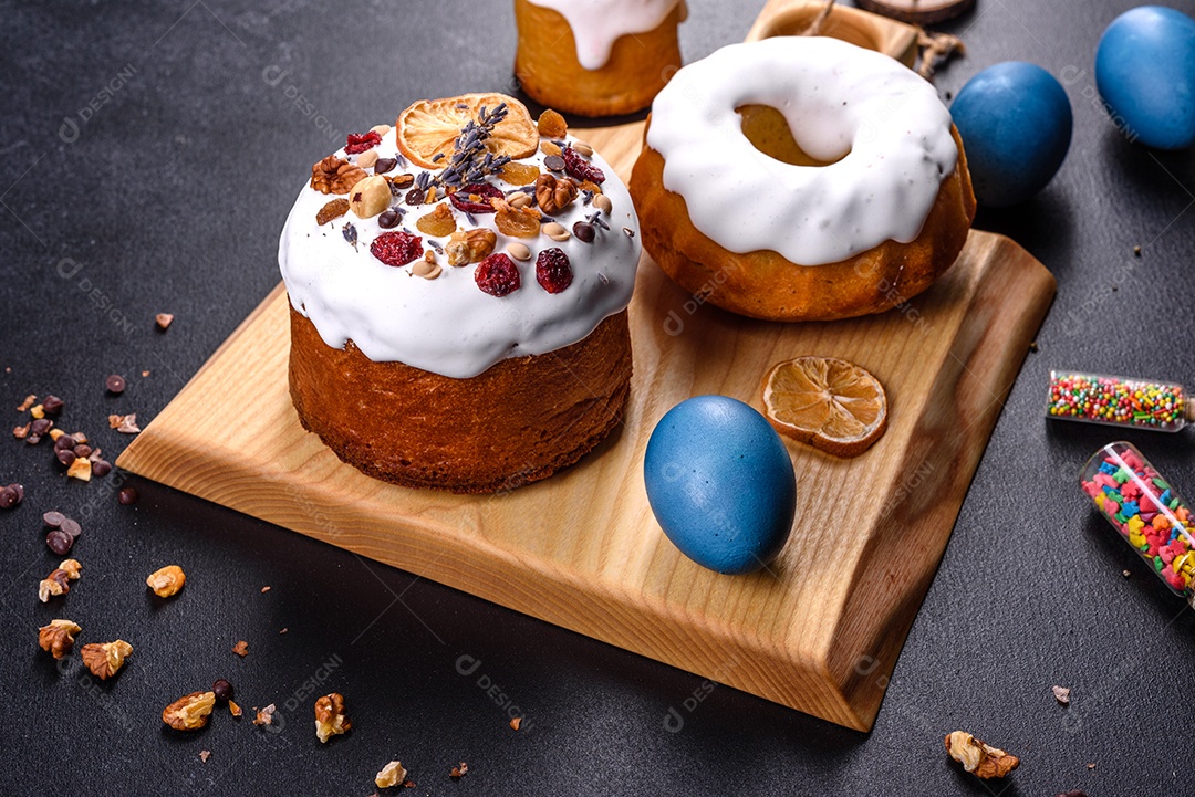 Bolos festivos com esmalte branco, nozes e passas com ovos de Páscoa na mesa festiva. Preparativos para a Páscoa