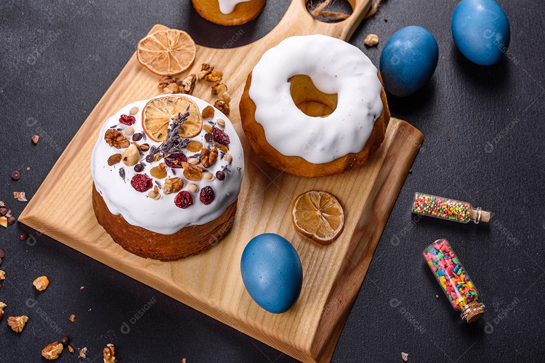 Bolos festivos com esmalte branco, nozes e passas com ovos de Páscoa na mesa festiva. Preparativos para a Páscoa