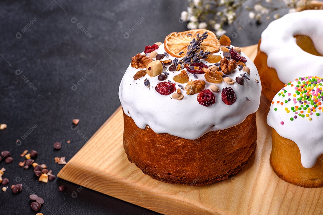 Bolos festivos com esmalte branco, nozes e passas com ovos de Páscoa na mesa festiva. Preparativos para a Páscoa