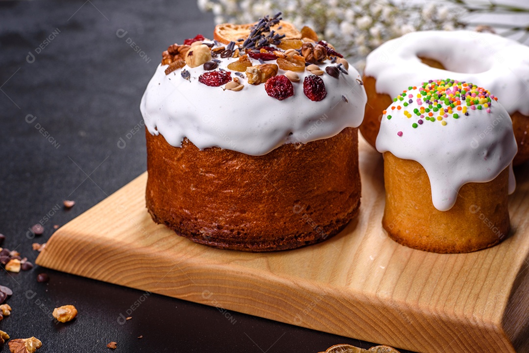 Bolos festivos com esmalte branco, nozes e passas com ovos de Páscoa na mesa festiva. Preparativos para a Páscoa
