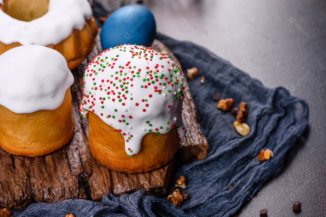 Bolos festivos com esmalte branco, nozes e passas com ovos de Páscoa na mesa festiva. Preparativos para a Páscoa