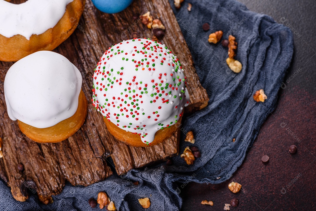 Bolos festivos com esmalte branco, nozes e passas com ovos de Páscoa na mesa festiva. Preparativos para a Páscoa