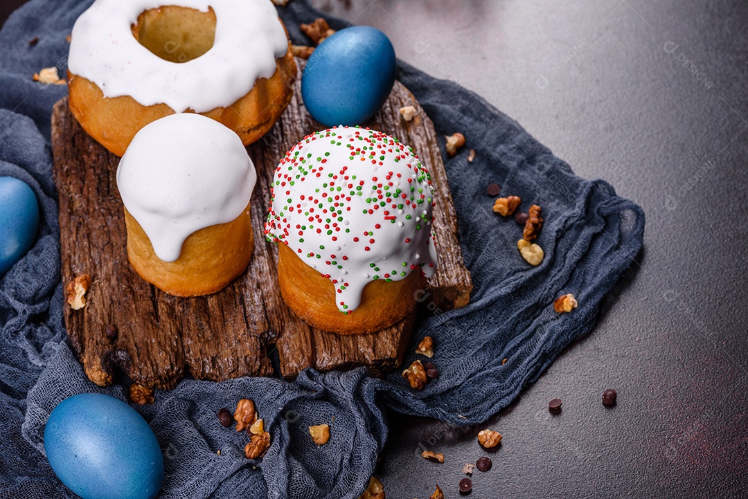 Bolos festivos com esmalte branco, nozes e passas com ovos de Páscoa na mesa festiva. Preparativos para a Páscoa