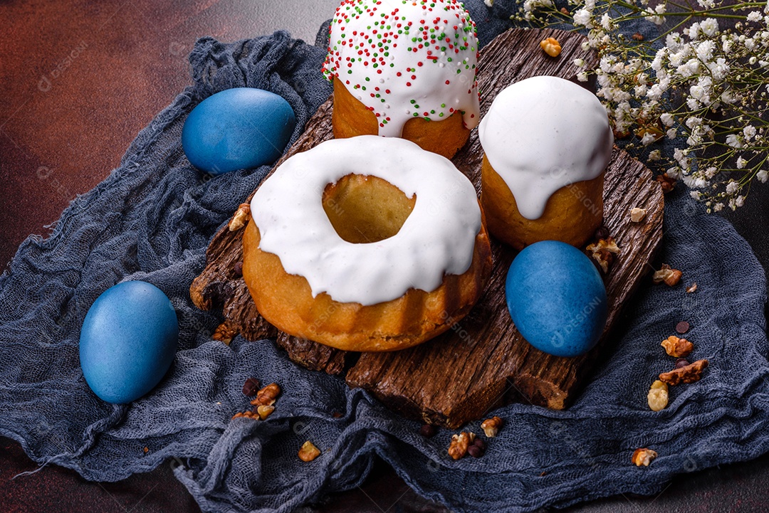 Bolos festivos com esmalte branco, nozes e passas com ovos de Páscoa na mesa festiva. Preparativos para a Páscoa